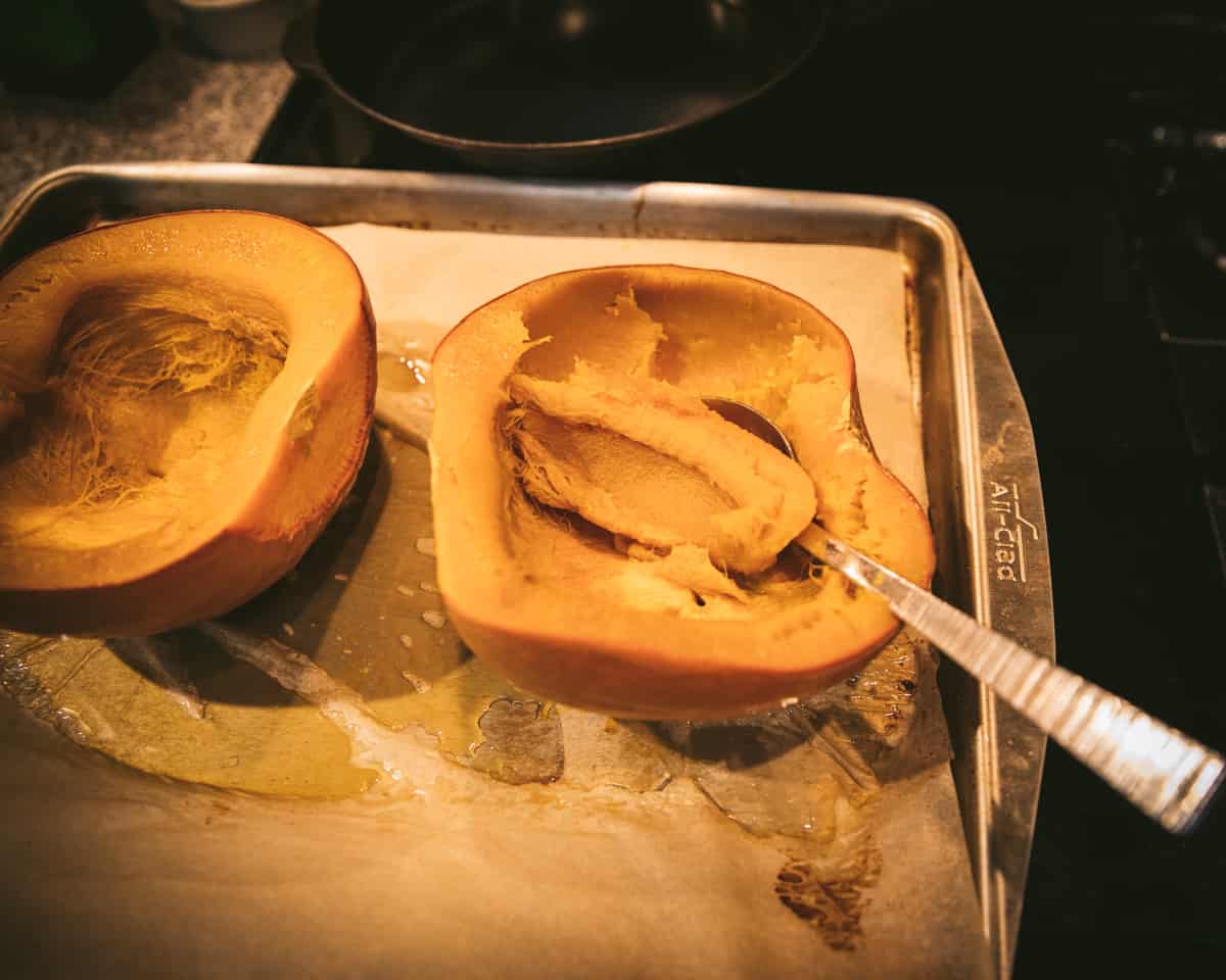 Roasted pumpkin flesh being scooped out with a spoon. 