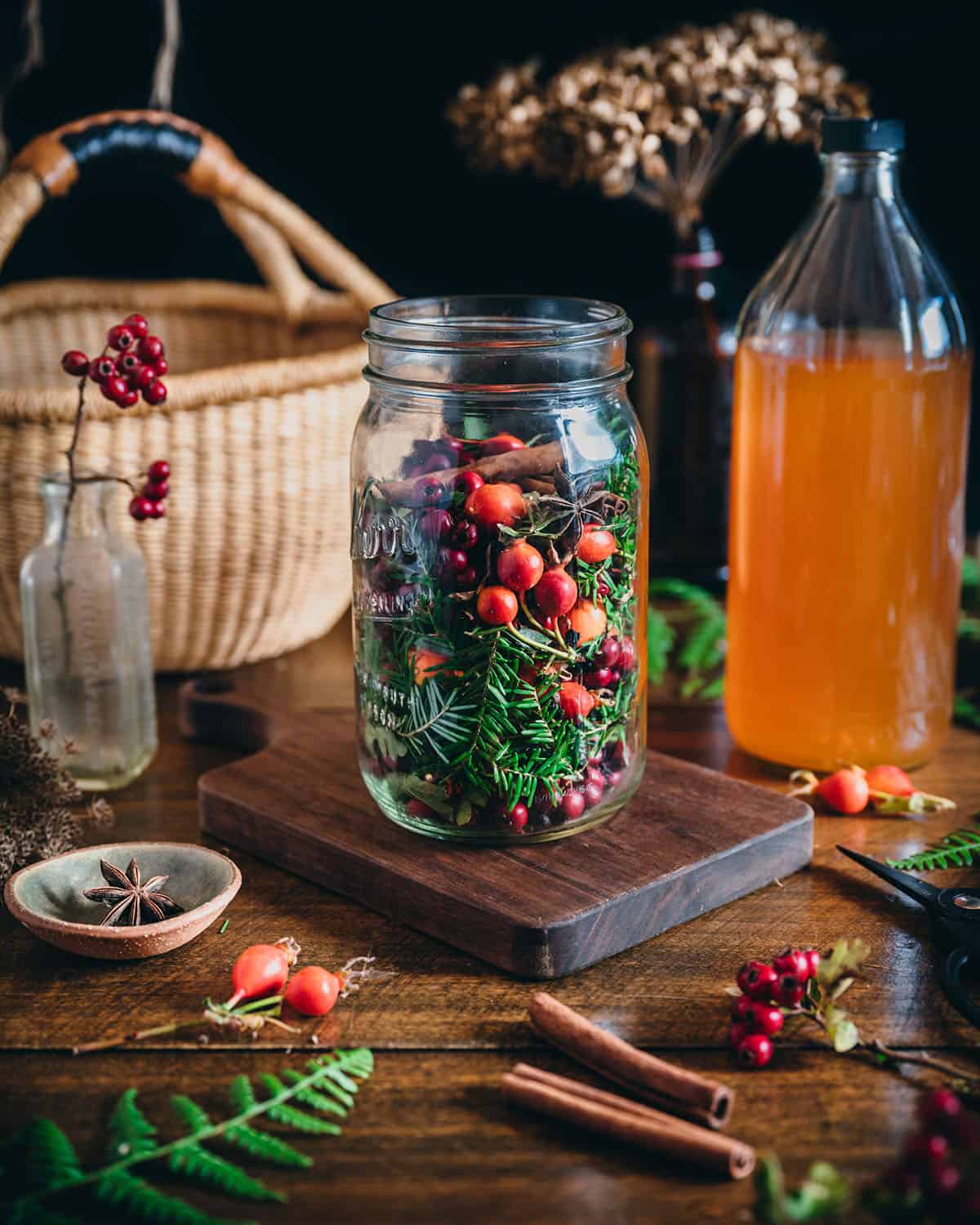 A jar filled with foraged plants and berries for infused vinegar. 