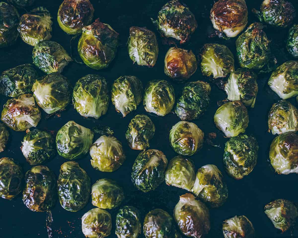 A sheet pan of halved Brussels sprouts cut-side down, with roasted tops that are golden brown.