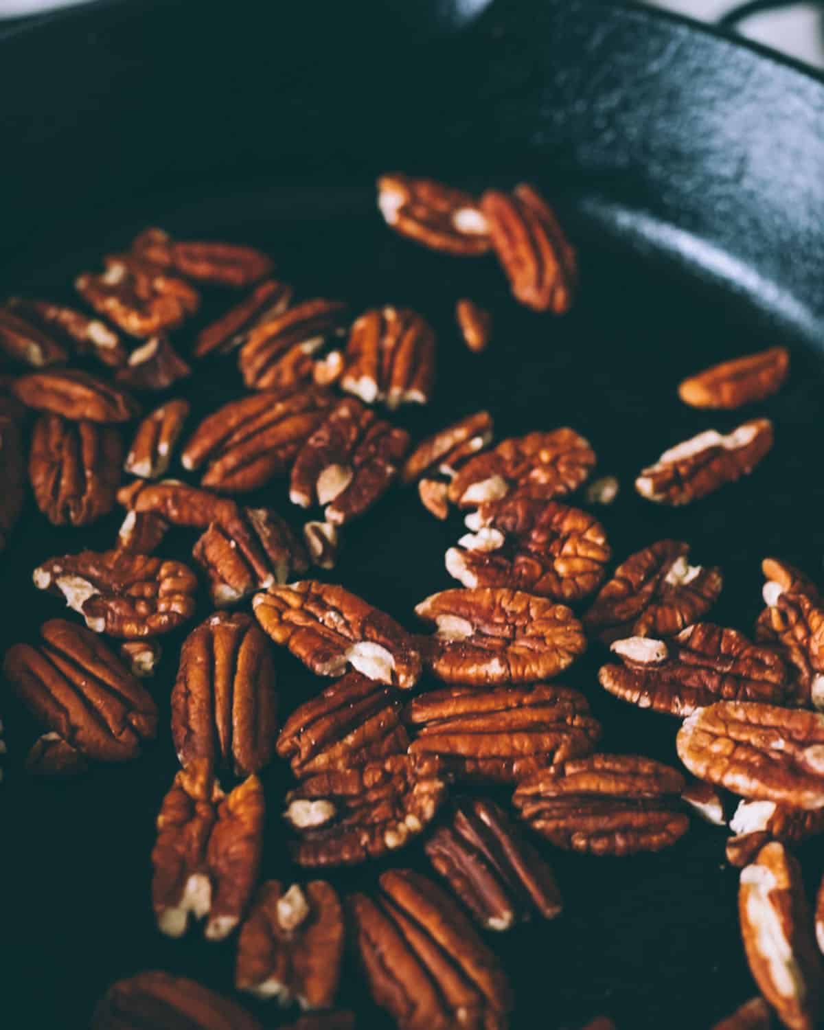 Pecan halves roasting in a cast iron skillet.