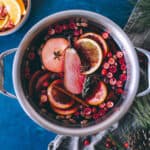 Mulled wine in a pot with garnishes, top view.
