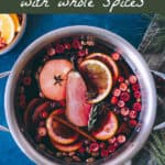 Top view of a pot of mulled wine with fresh garnishes, with a top banner that reads mulled wine with whole spices.