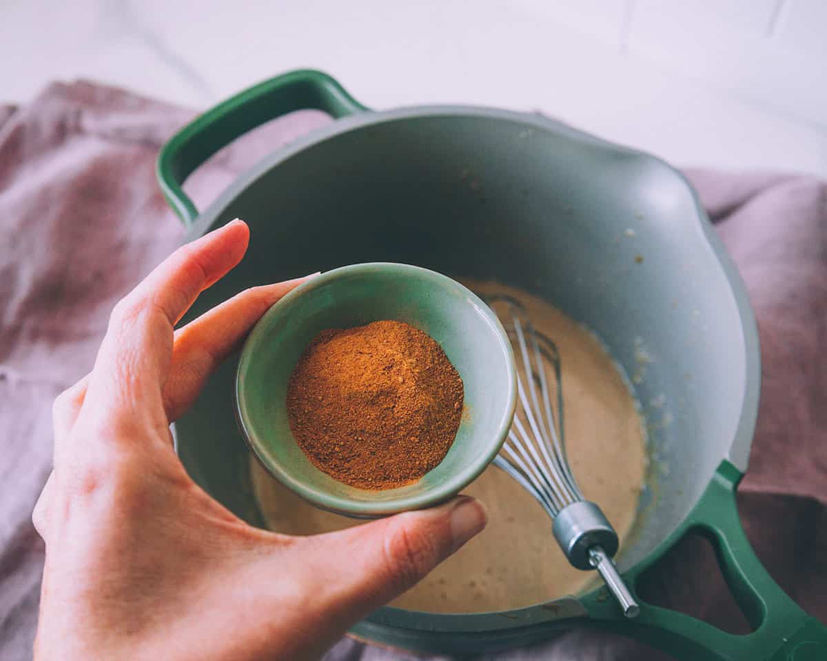 Rosehip and acerola powders in a small dish being ready to be poured onto a pot with the gelatin mixture with a whisk sitting in it.