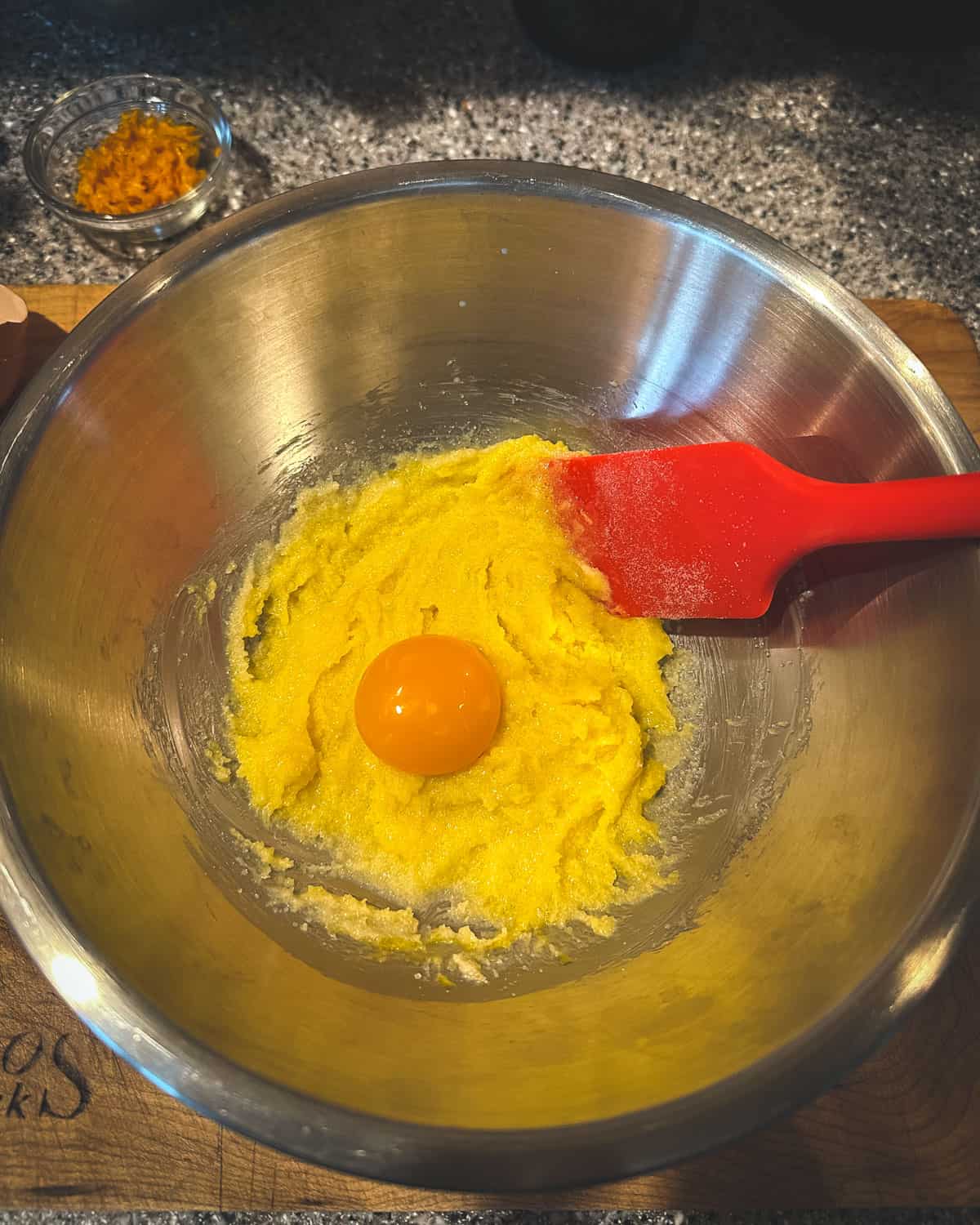 A metal bowl with egg yolks and reduced sugar mixture. 