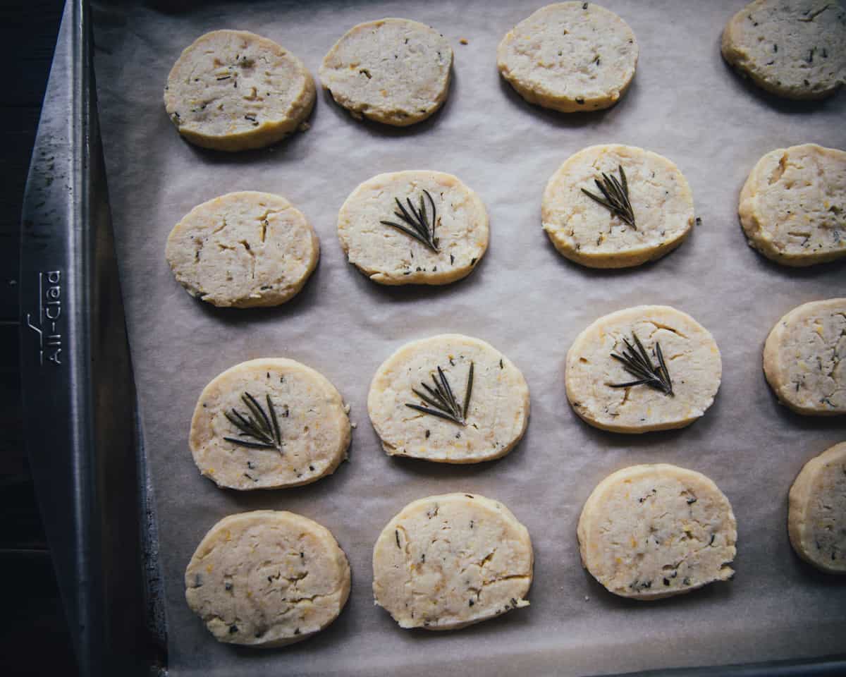 A baking sheet lined with parchment with baked lemon rosemary shortbread cookies. 
