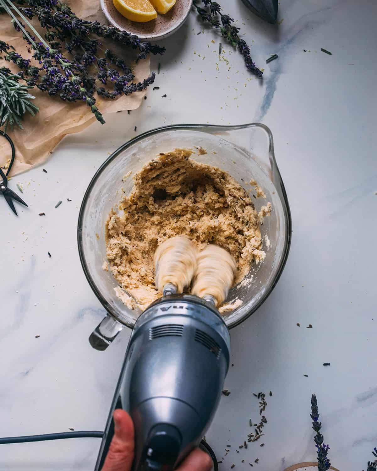 The dough in a clear mixing bowl taking form while it's being mixed with a hand mixer.