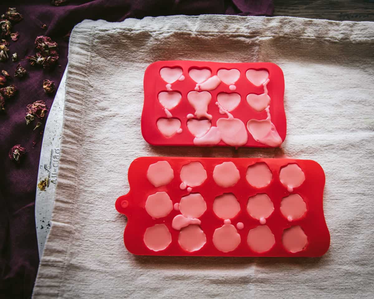 Red heart and flower molds with hardened lotion bars ready to be popped out.