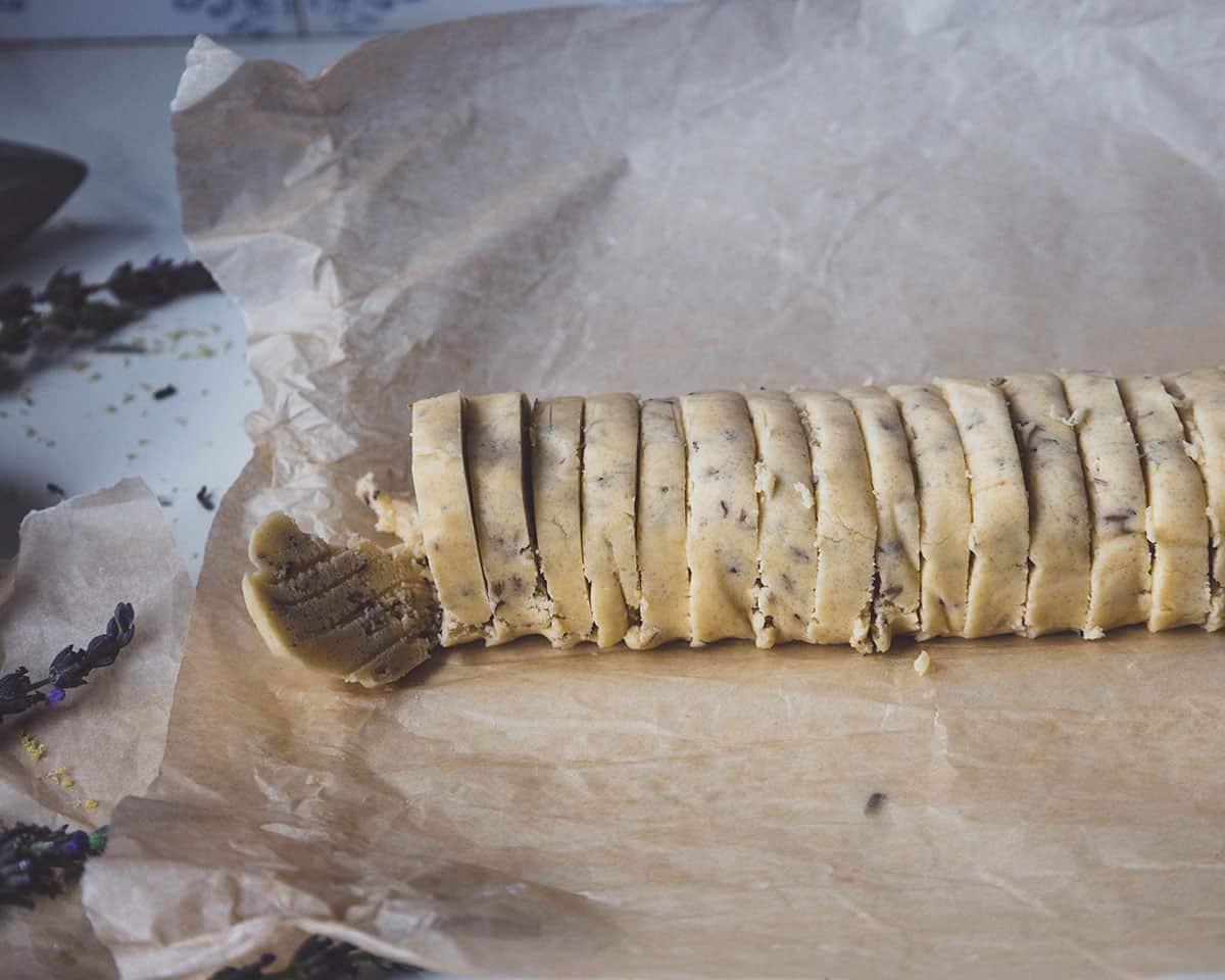 Parchment paper unwrapped showing half the dough log sliced into 1/4 inch rounds.