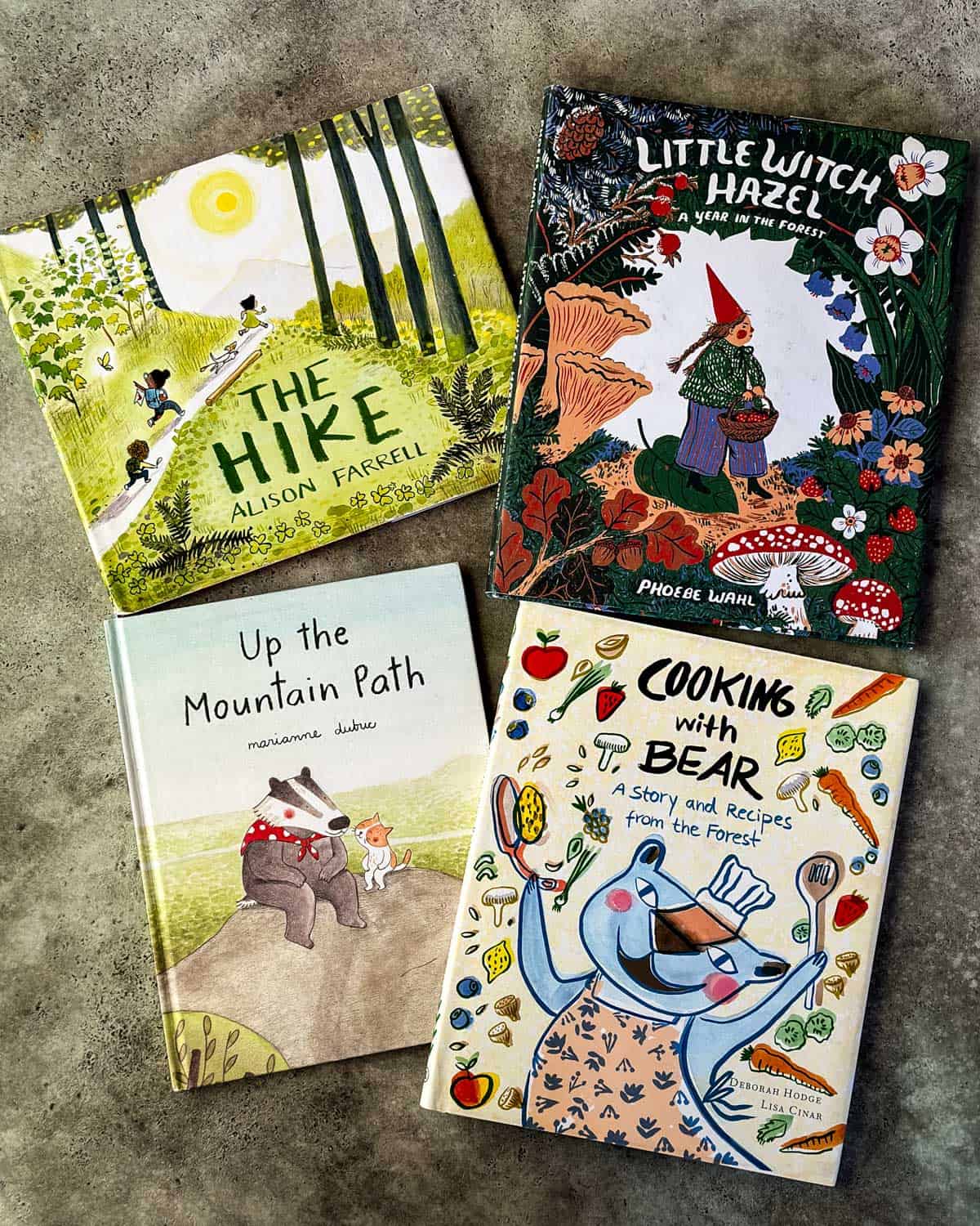 4 kids foraging storybooks laid face up on a grey surface, all with beautiful illustrations. 