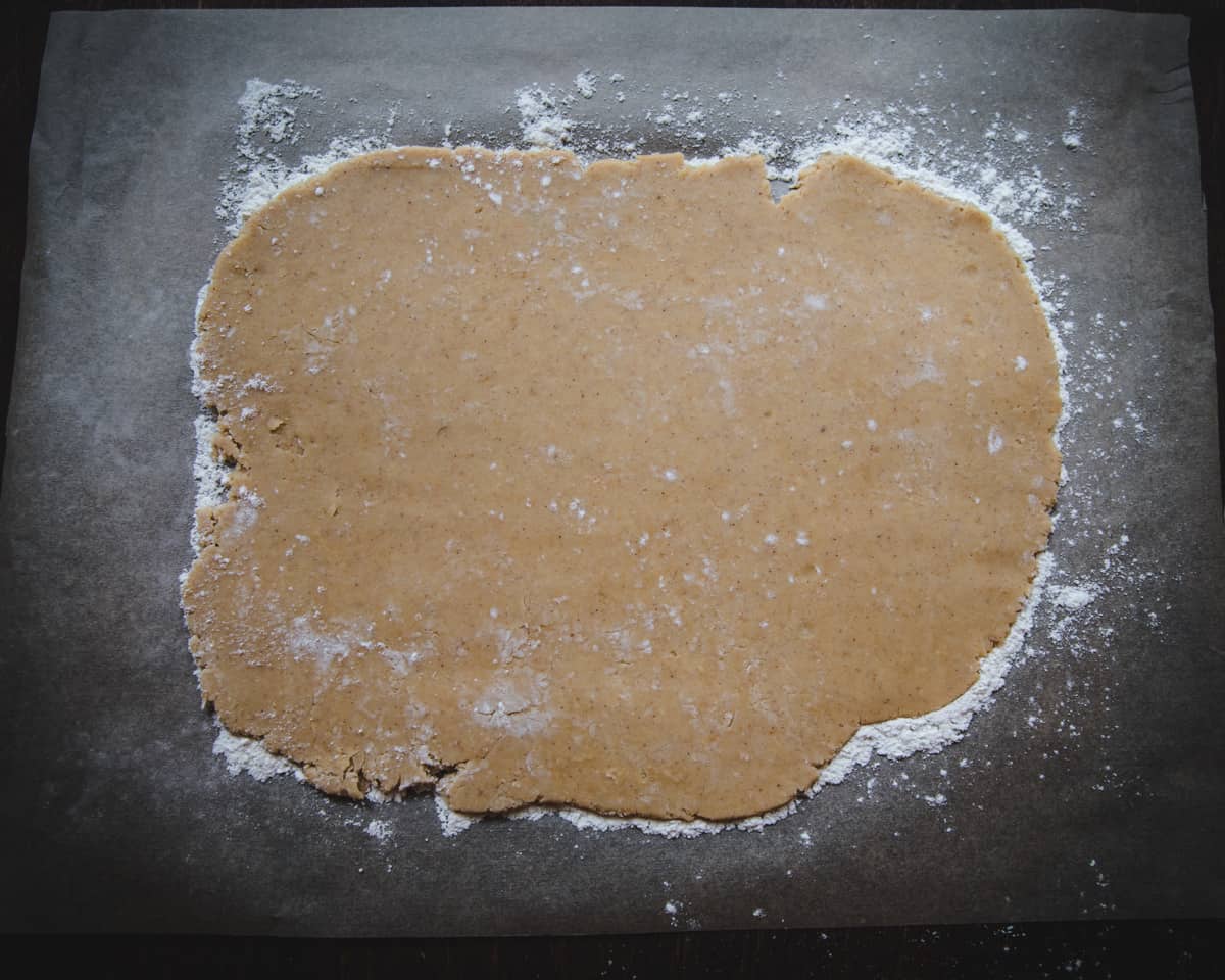 One dough half rolled out onto floured parchment paper. 