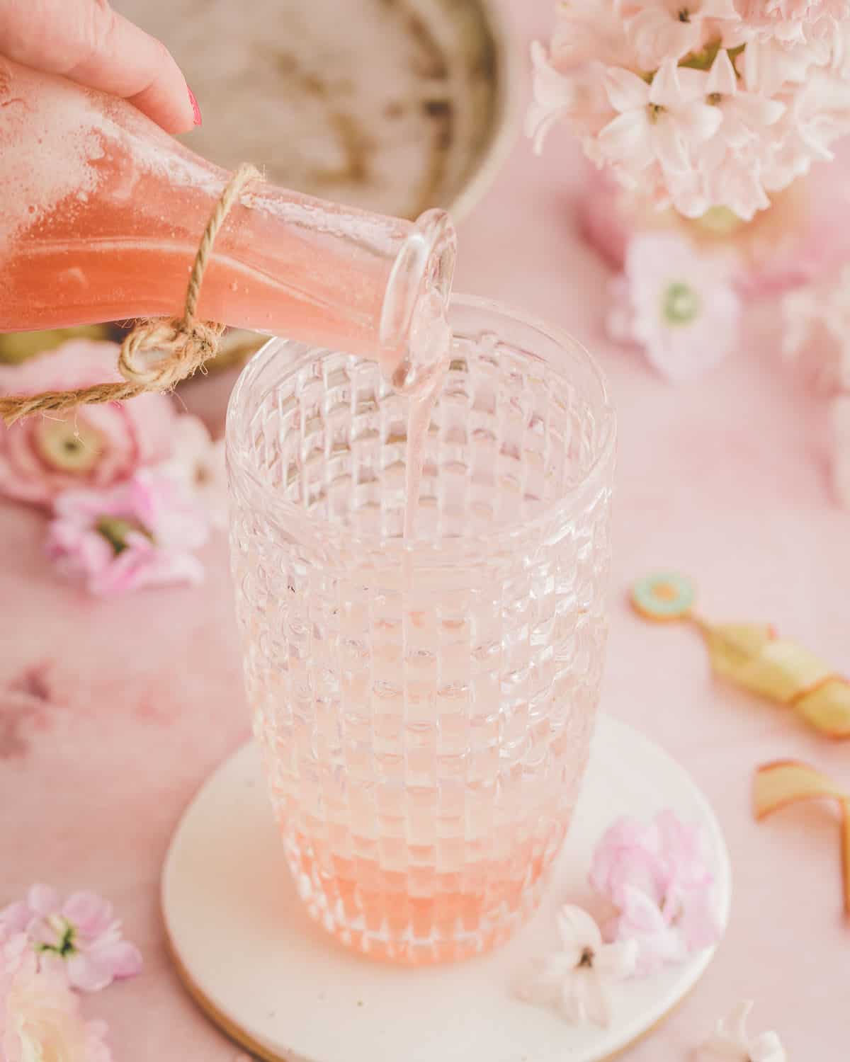 Rhubarb syrup pouring into a vintage glass cocktail shaker. 