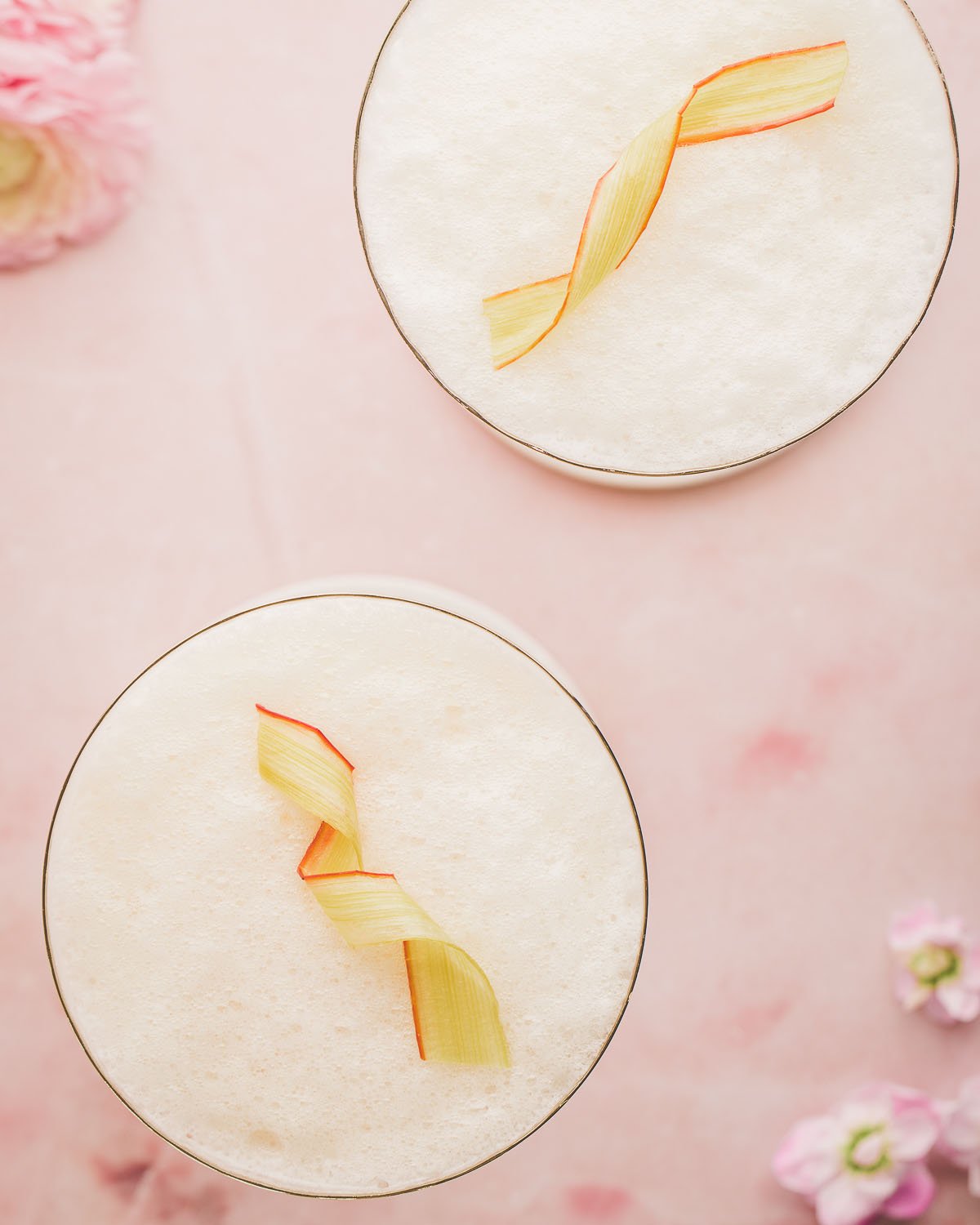 Cocktails with candied rhubarb ribbons as garnish on the top. 