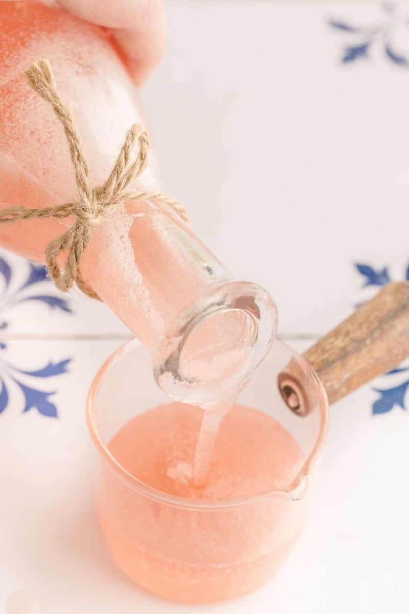 rhubarb syrup pouring into a glass with a white background. 