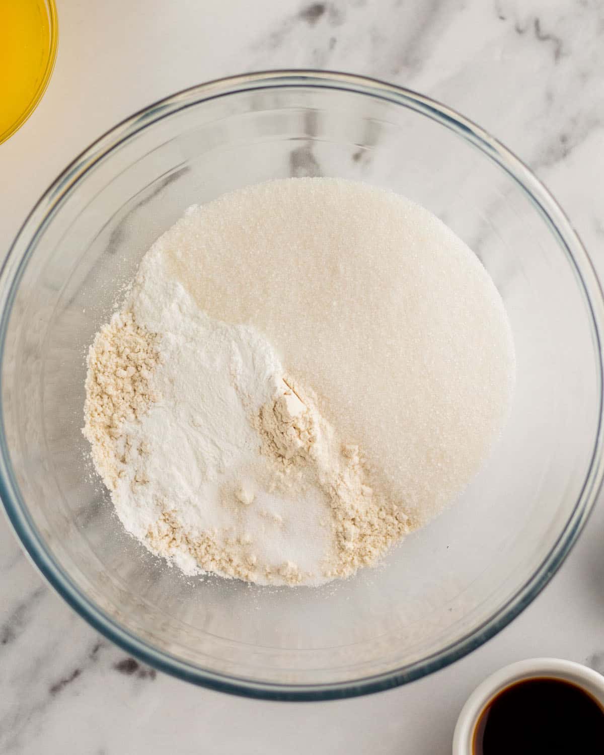 Dry ingredients in a clear mixing bowl on a white and gray granite counter. 