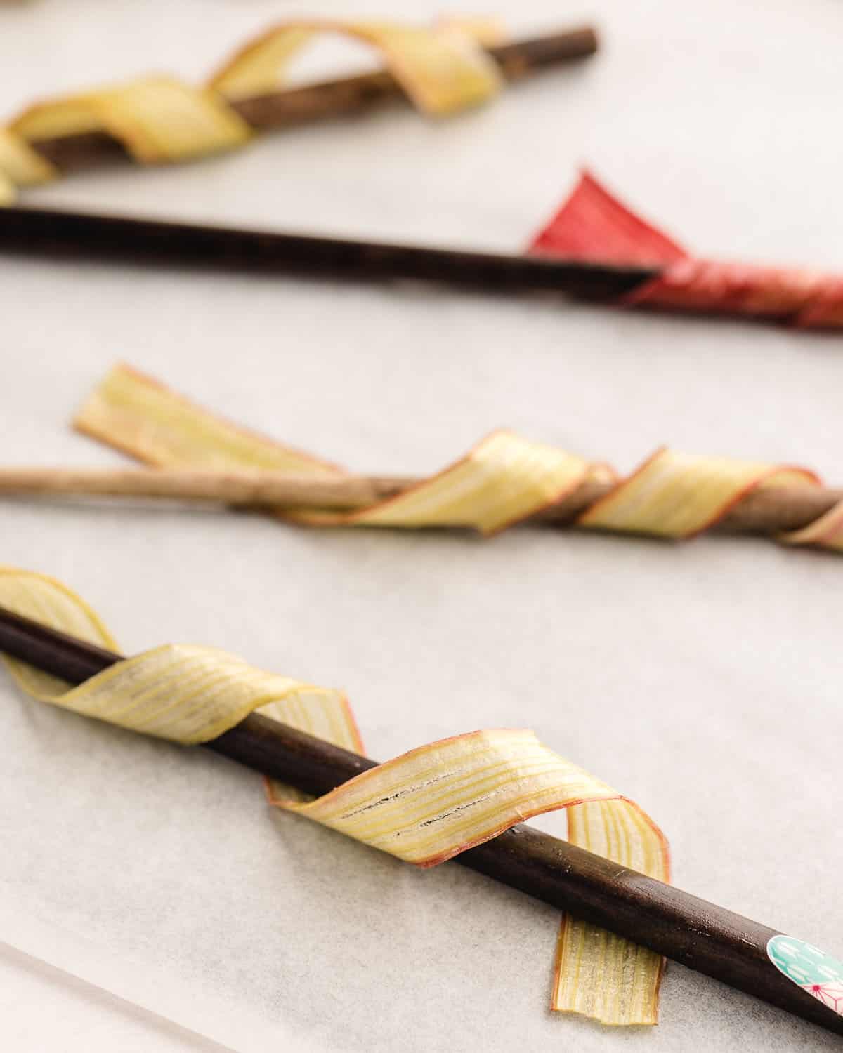 Rhubarb strips wrapped around wooden chopsticks. 