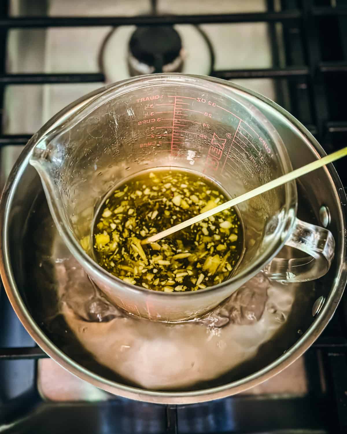 A makeshift double boiler with a bamboo skewer stirring oils. 