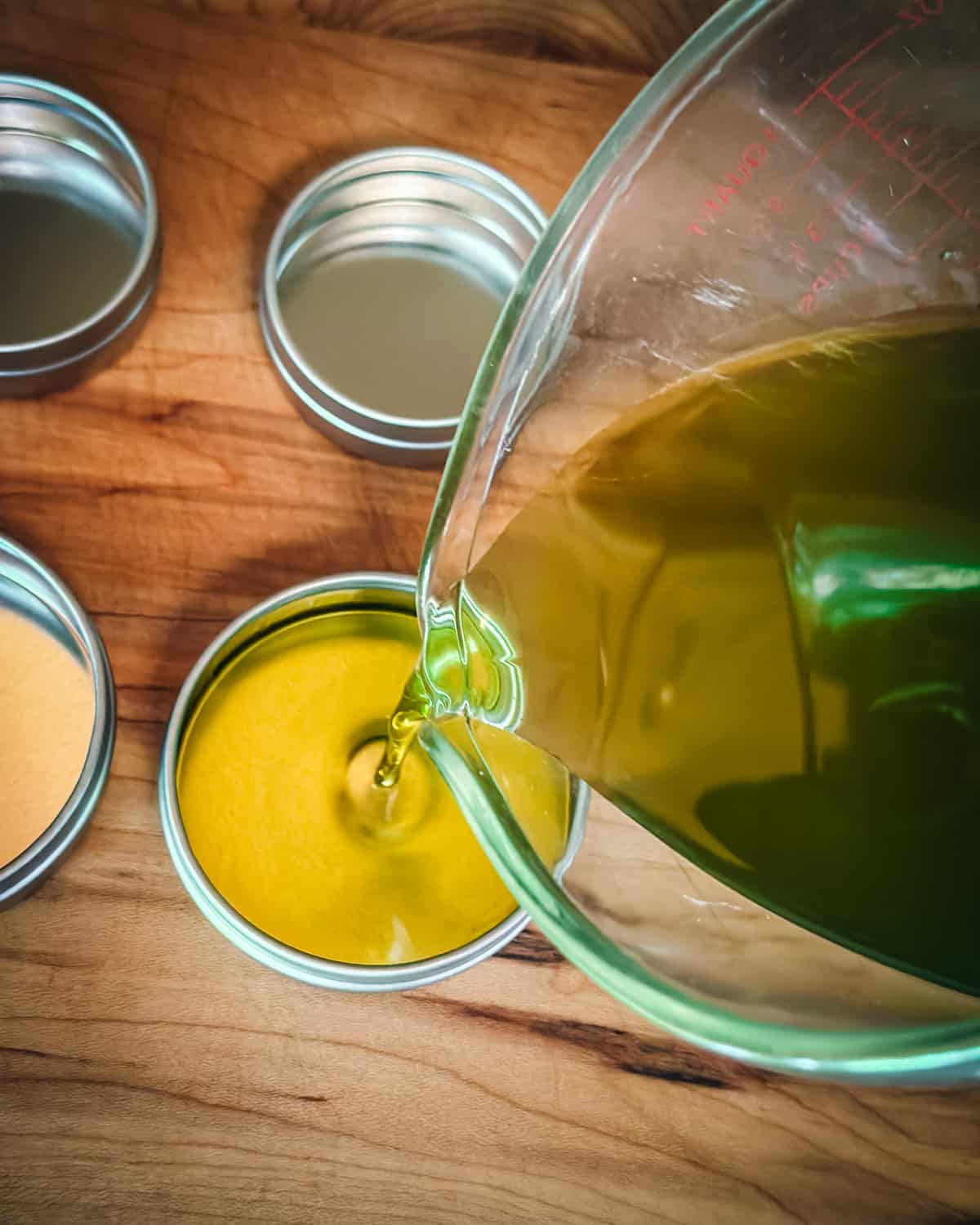 Plantain salve liquid pouring into tins. 