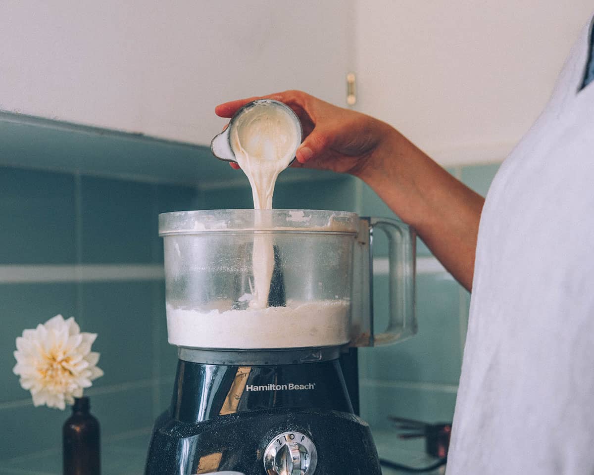 Side view of sourdough starter pouring into the food processor.