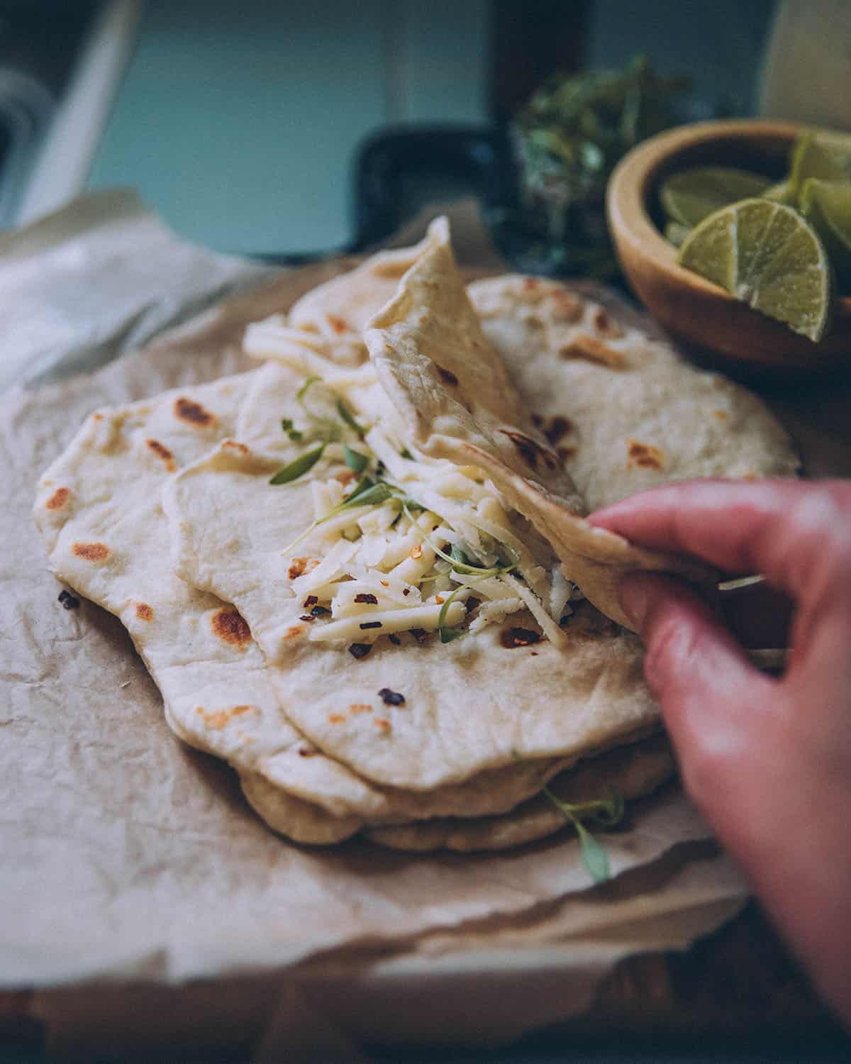 A stack of sourdough tortillas, the top one folded with taco ingredients. 