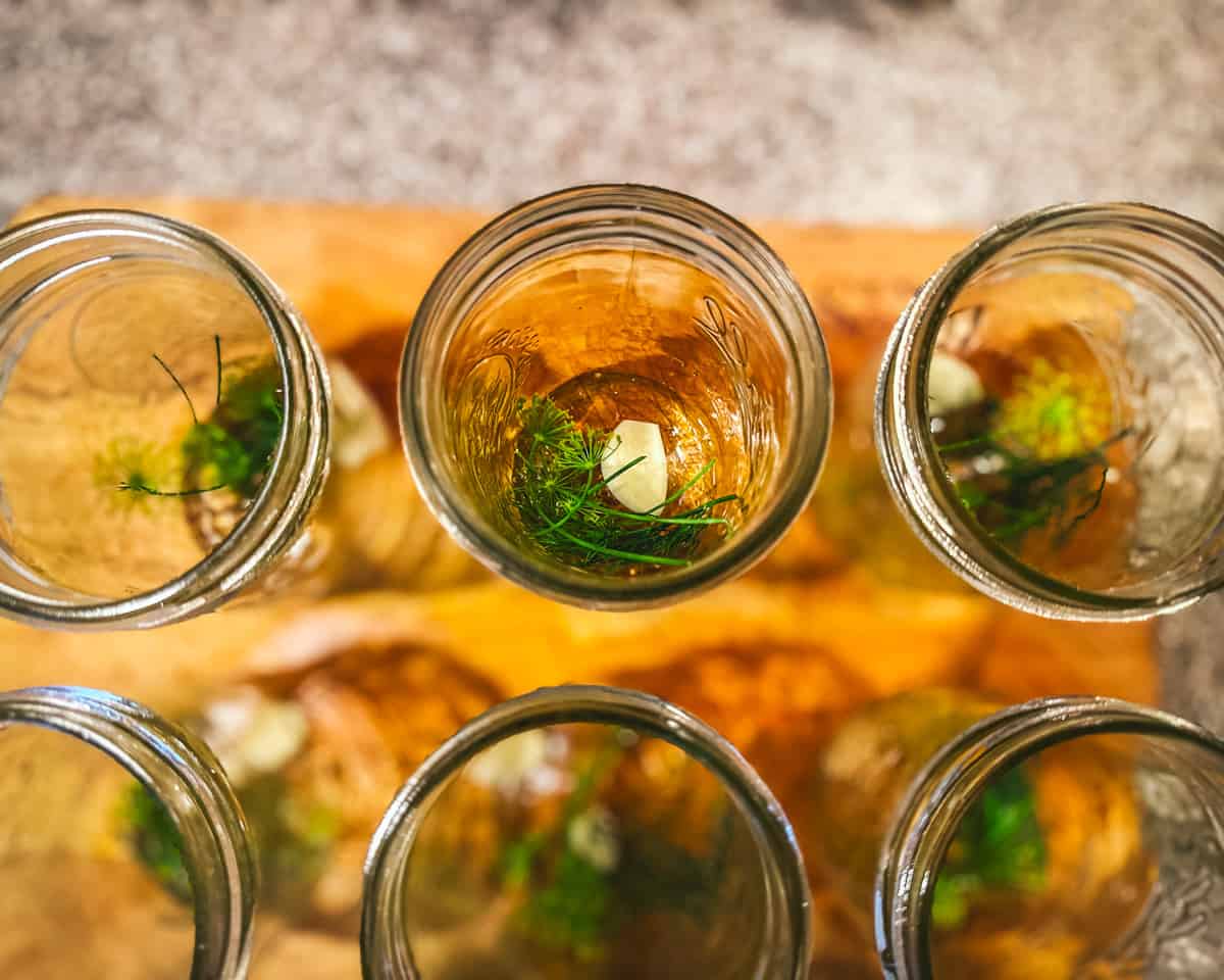 Open jars with pickling ingredients in them, top view.