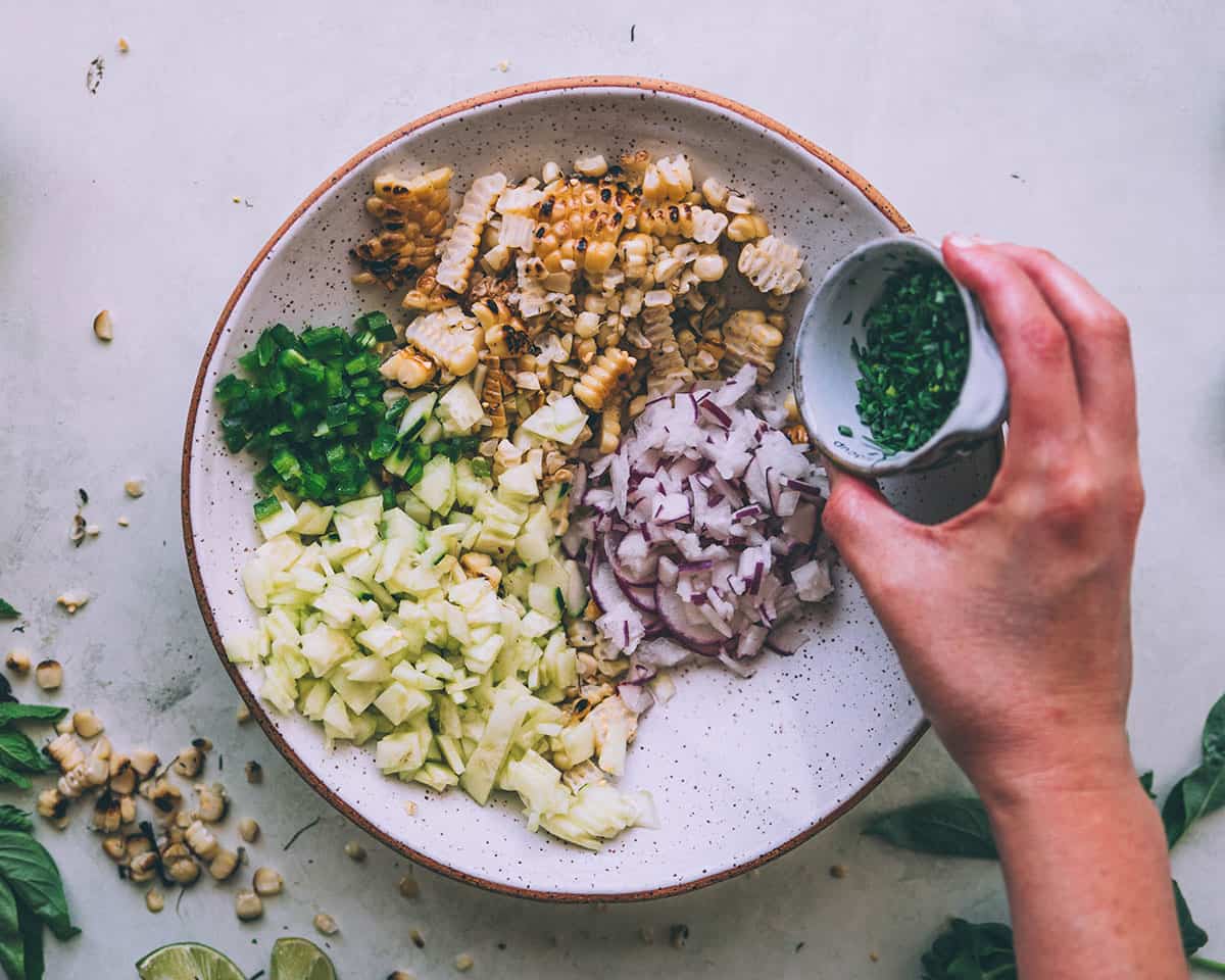 Fresh herbs being added to the corn salad mix. 