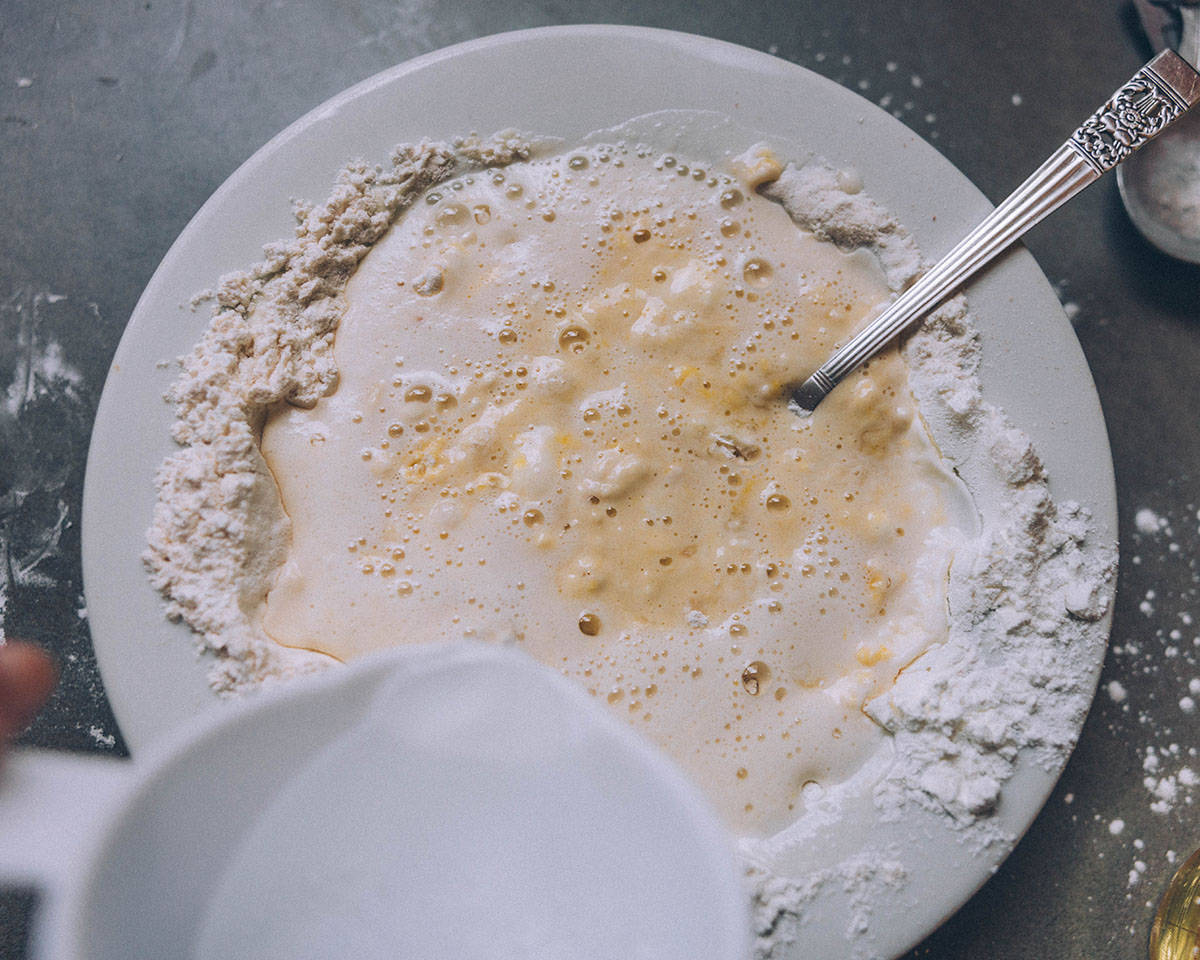 A white bowl of batter with sparkling water added and stirred, it's a little bit lumpy. 