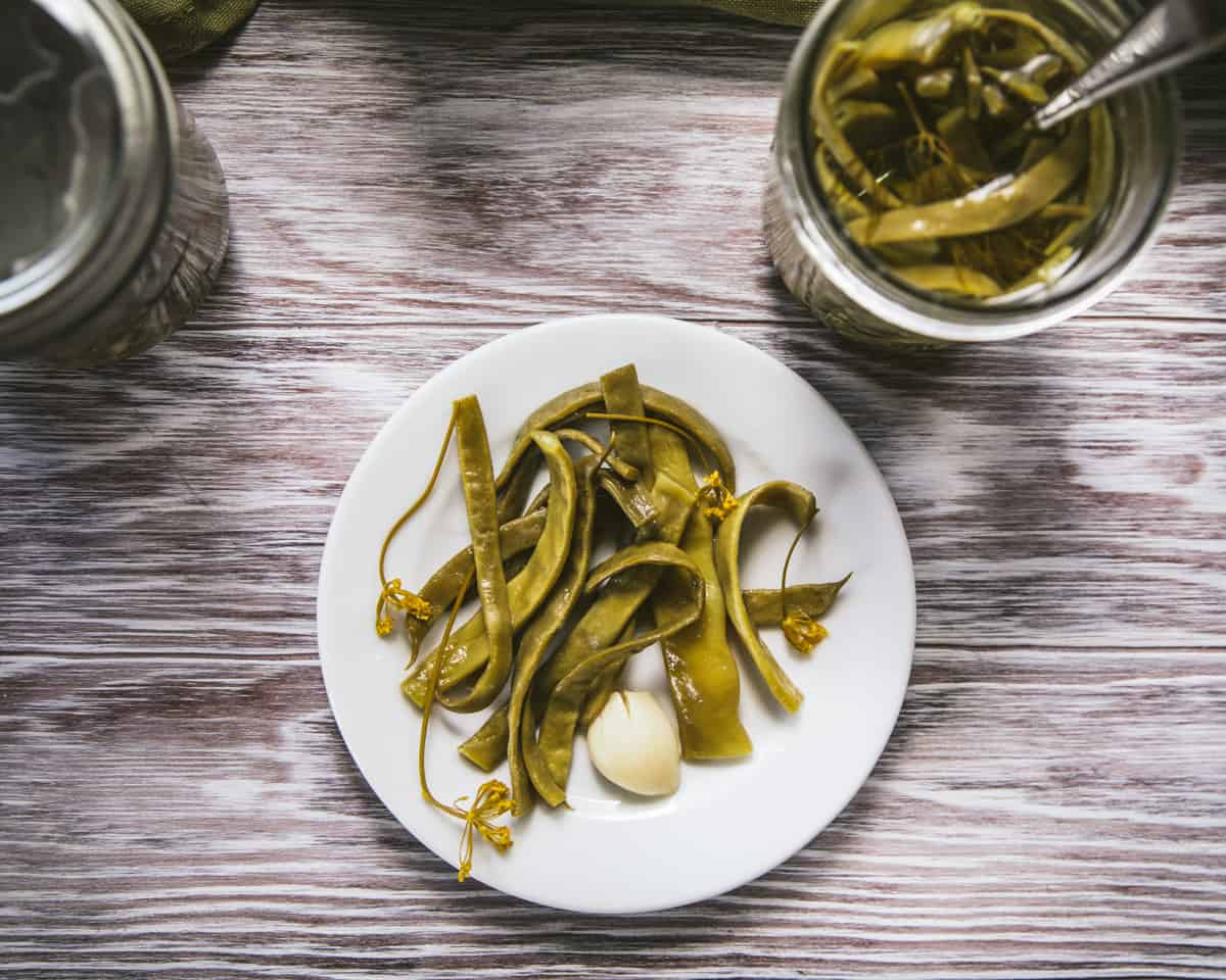 Dilly beans on a white plate on a wood surface, top view. 