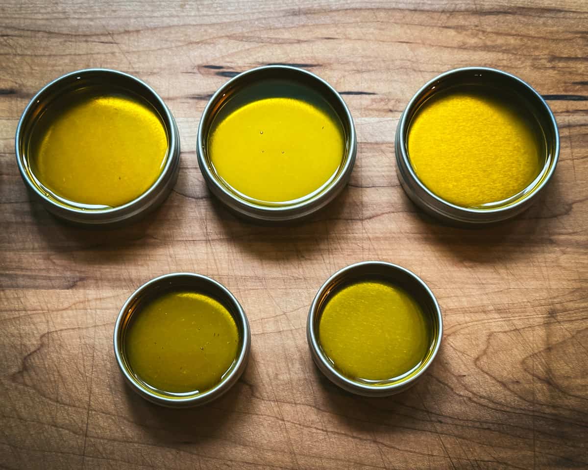 Tins filled with yarrow salve, sitting out to cool and set on a wood cutting board. 