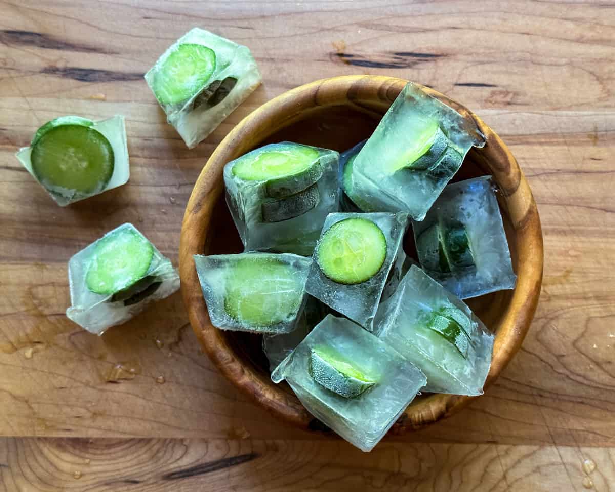 cucumber slices frozen in ice cubes in a wooden bowl