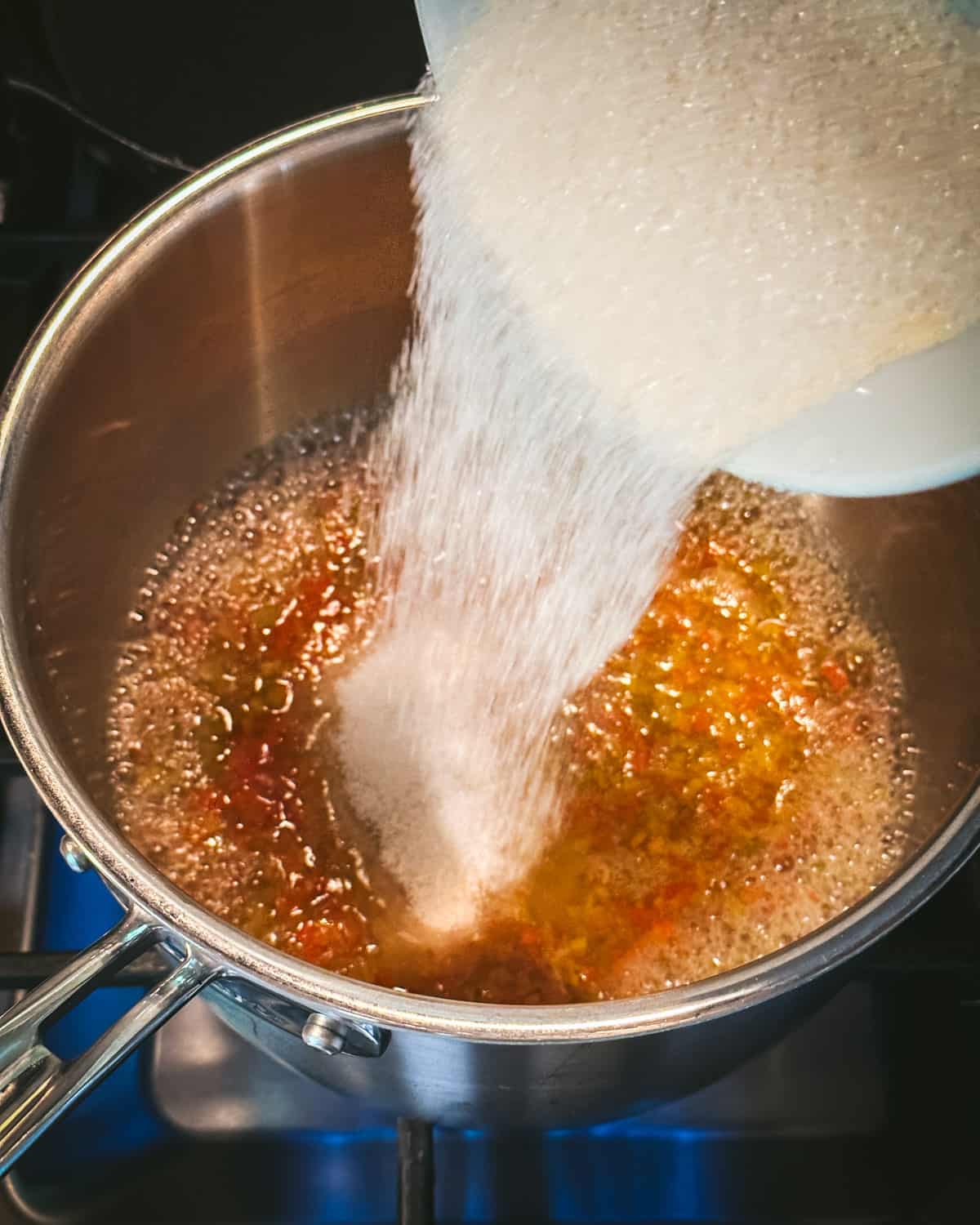 Sugar pouring into the boiling pepper jelly mixture. 