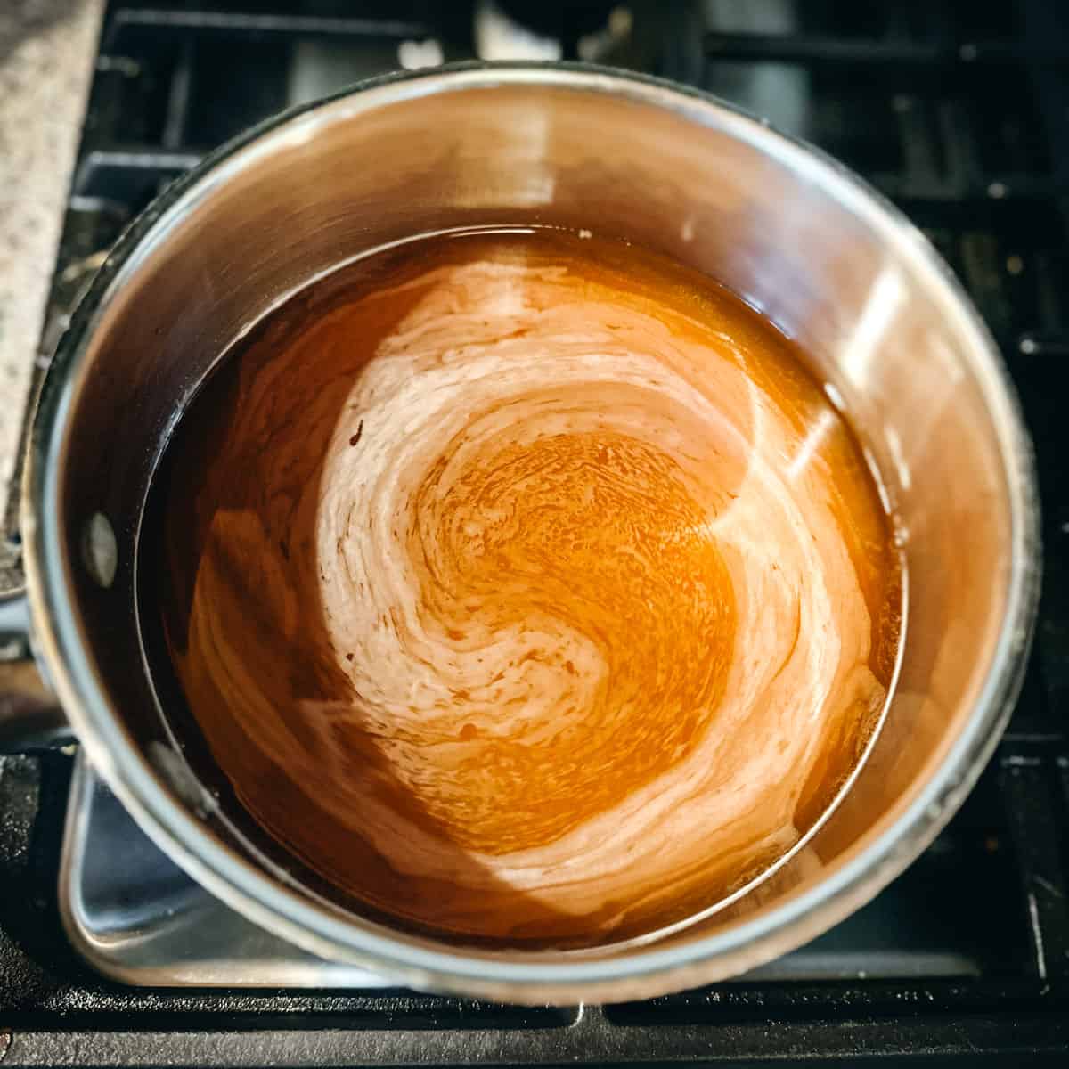 A small pot on the stove heating the pickling brine, top view.