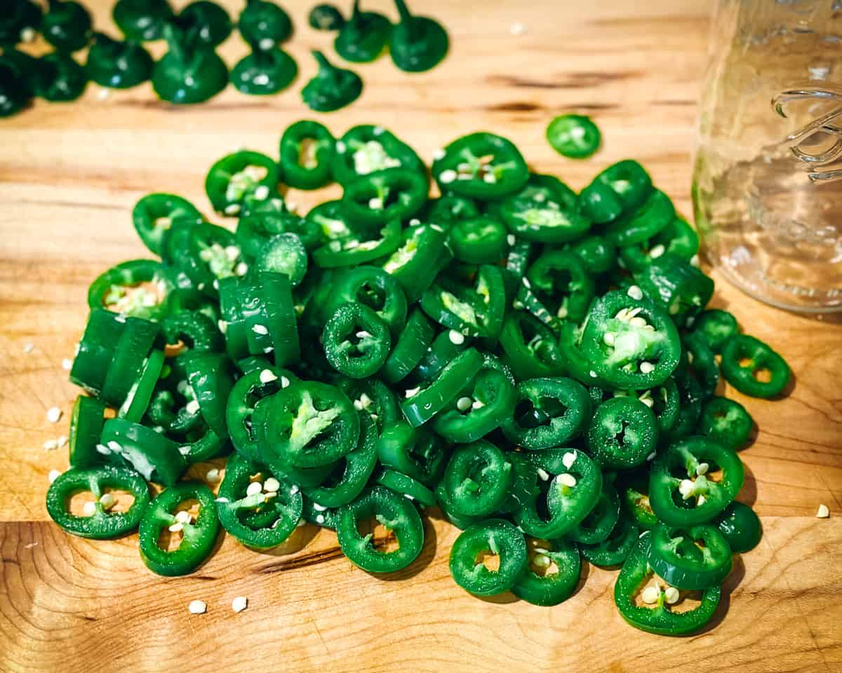 Sliced jalapeños on a wood cutting board. 