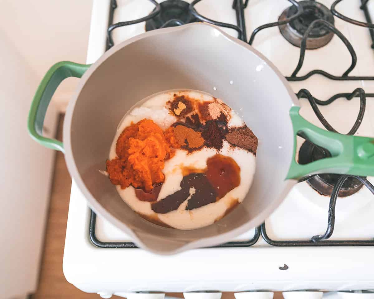 A small pot with a green handle that shows coconut butter melting with the spices and pumpkin puree, top view. 