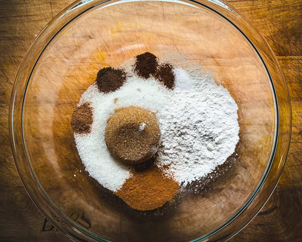 Ground spices and arrowroot powder in a clear bowl, unmixed. Top view. 