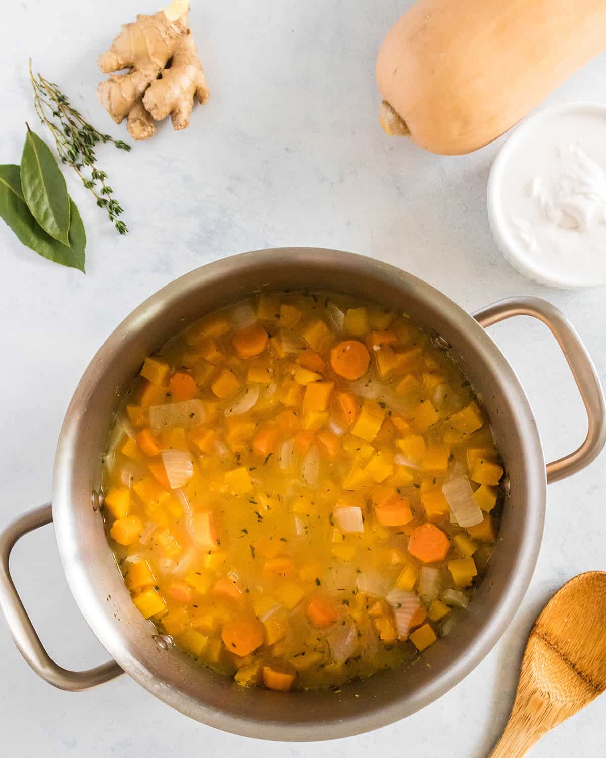 Simmering soup with butternut squash and vegetables in a pot, top view. 