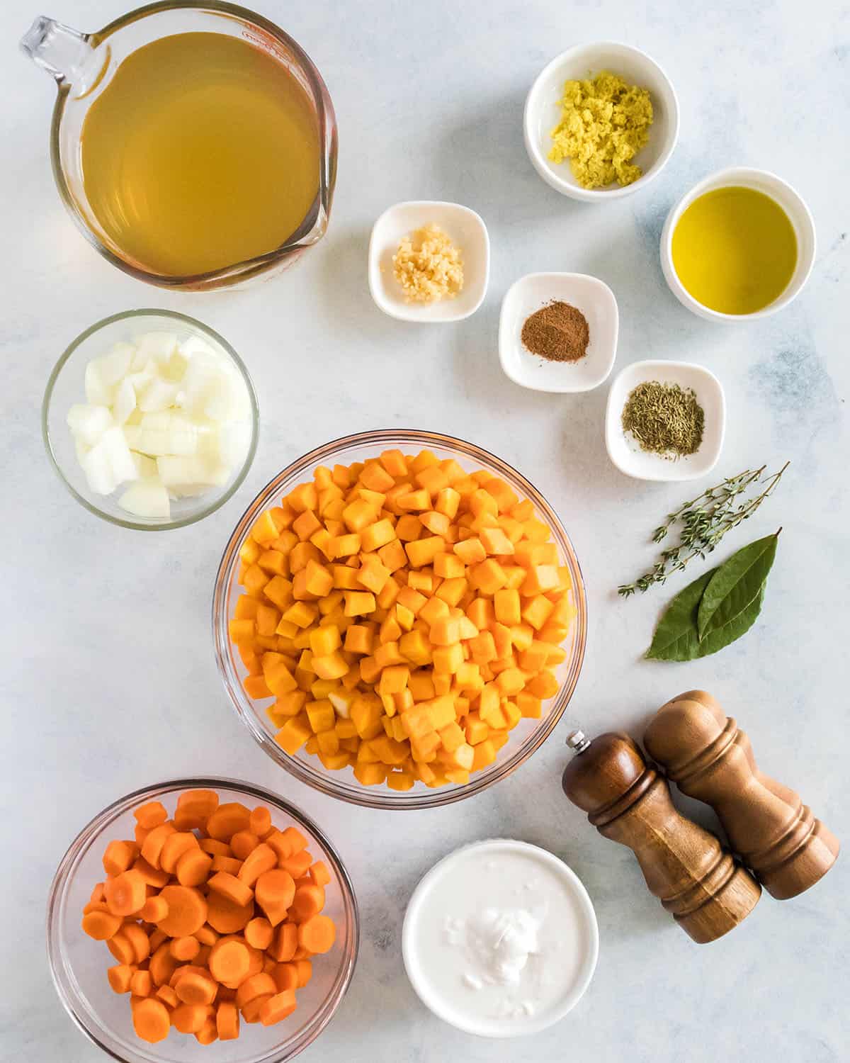 Bowls of ingredients for butternut squash soup, with wood salt and pepper grinders. Top view. 