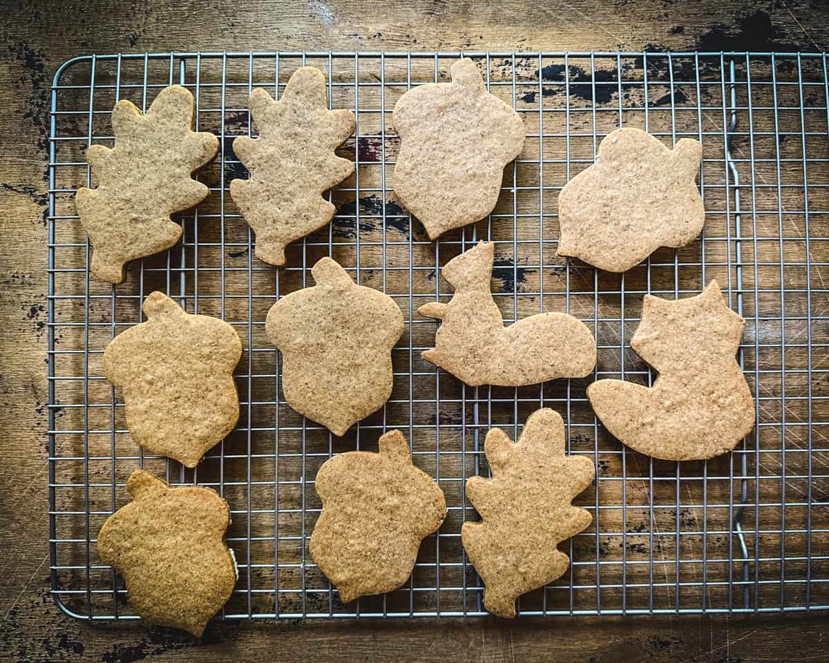 Acorn flour cookies baked and cooling on a rack on a dark wood surface. 