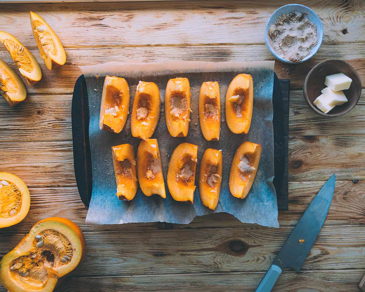 Pumpkin wedges on a baking sheet with brown sugar coating. 