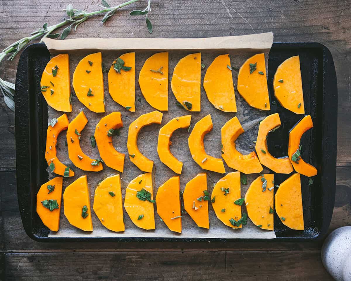 Squash slices on a baking sheet, lined up on parchment paper. 