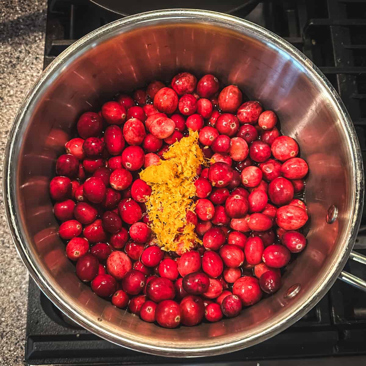 Whole cranberries and orange zest in a pot, top view. 