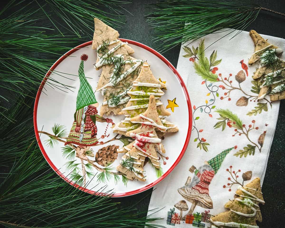 Pine tree cookies on a holiday gnome plate surrounded by pine needles. 