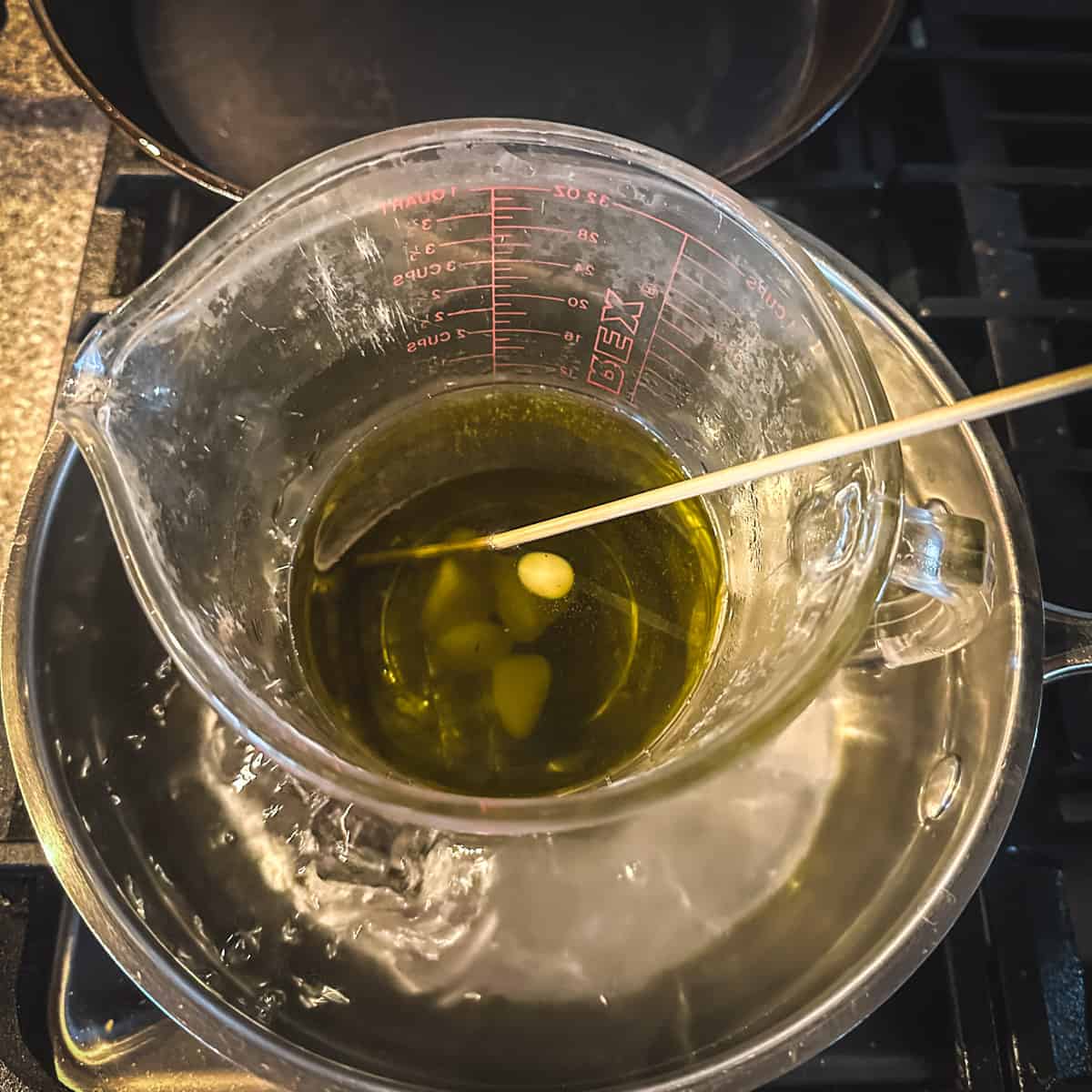 Pine oil and beeswax melting in a makeshift double boiler, being stirred with a wood skewer. 