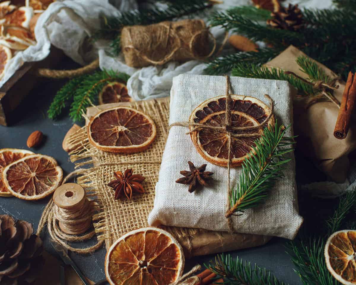 A wrapped package with white paper, dried orange slices, and natural trimmings. 