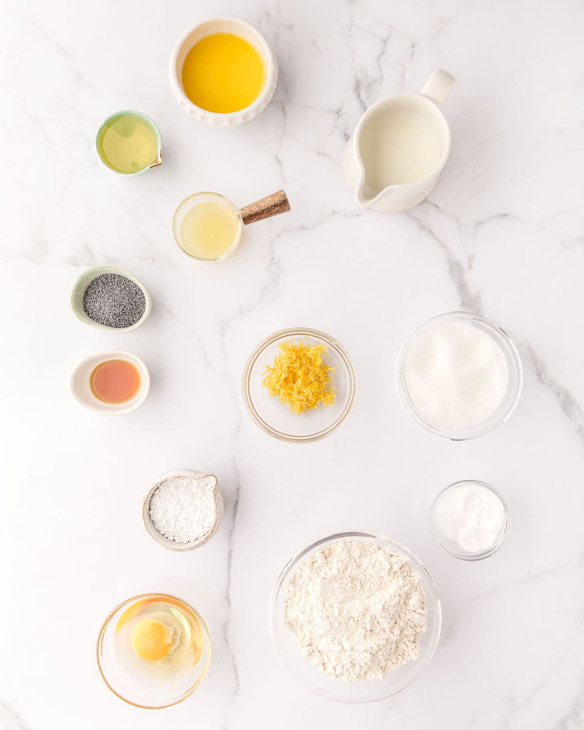 Ingredients measured in small bowls on a white countertop, top view. 