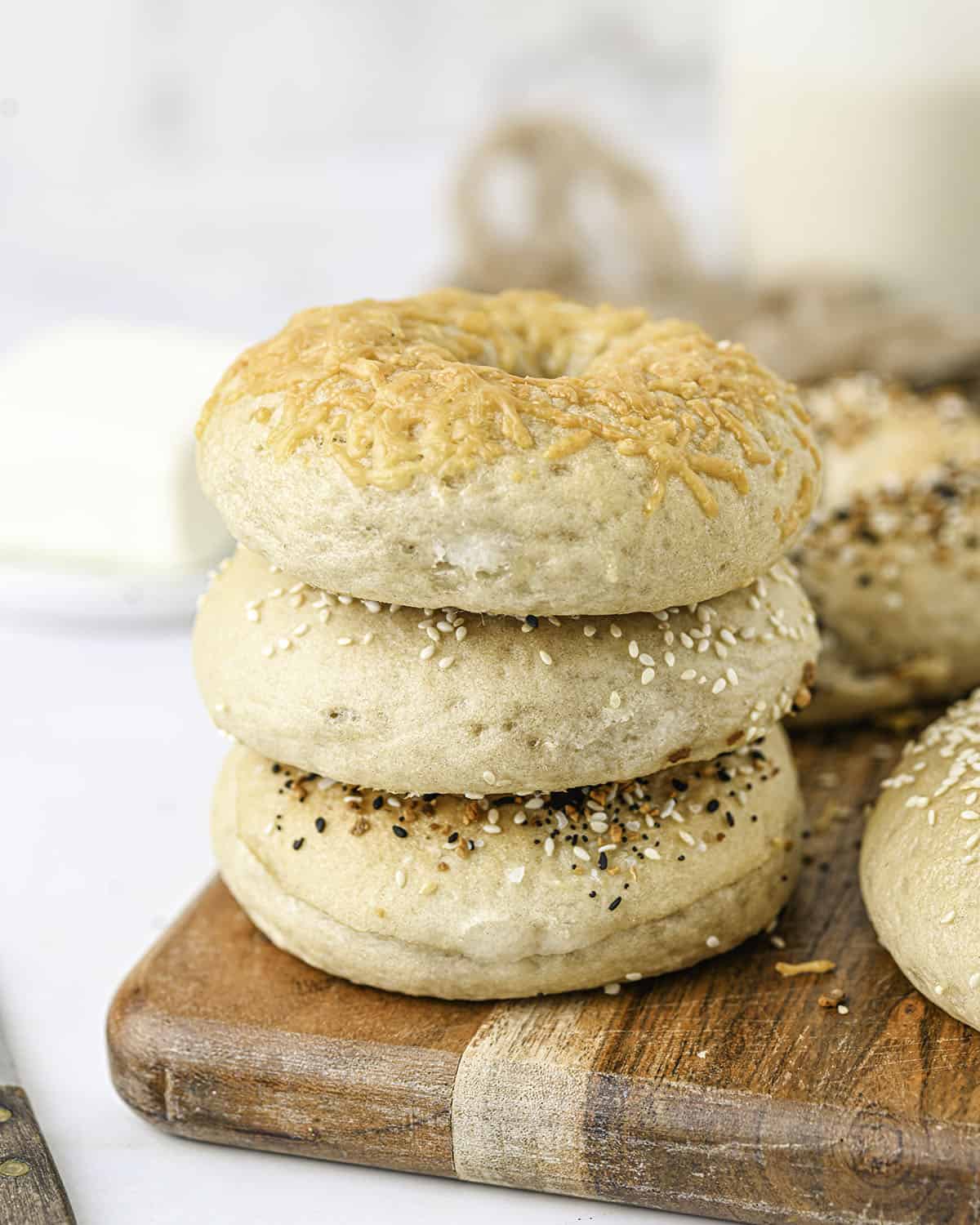 A stack of sourdough bagels on a wood cutting board. 