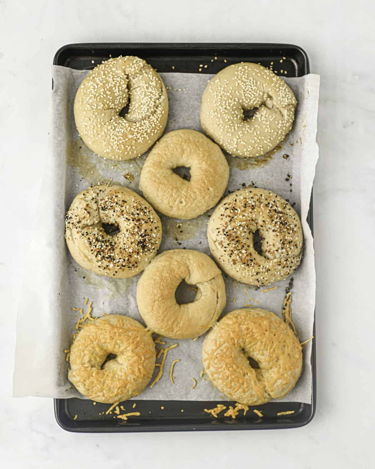 Baked sourdough bagels on a baking sheet with parchment paper. 