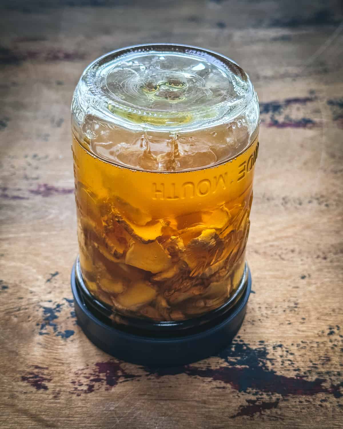 An upside down jar with a lid on it with fermenting ginger honey. 