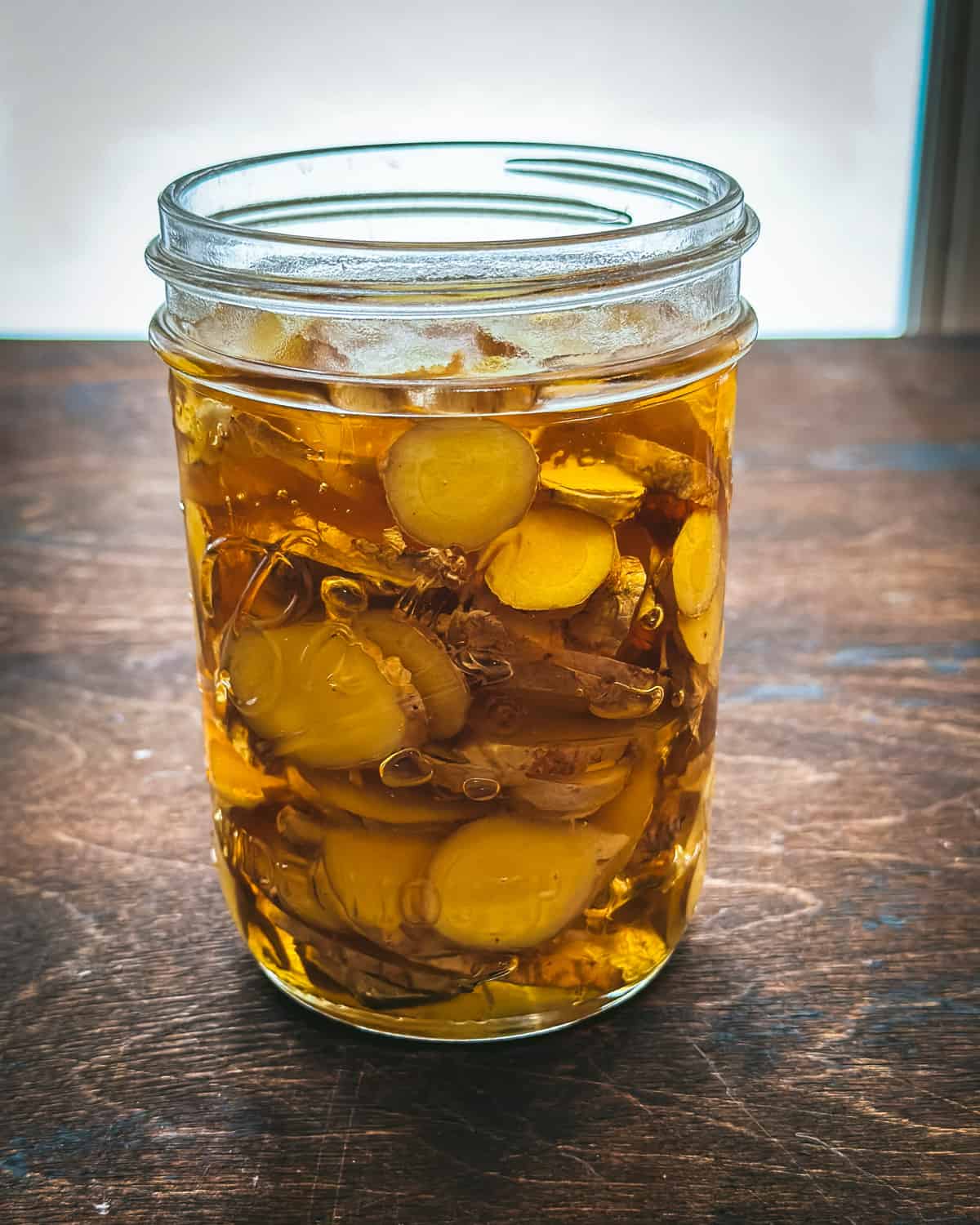 Honey and ginger in a jar on a dark wood surface. 