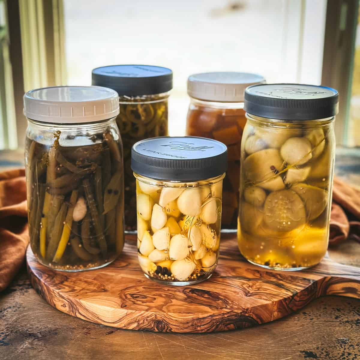 Several jars of different types of quick refrigerator pickles on a wooden table