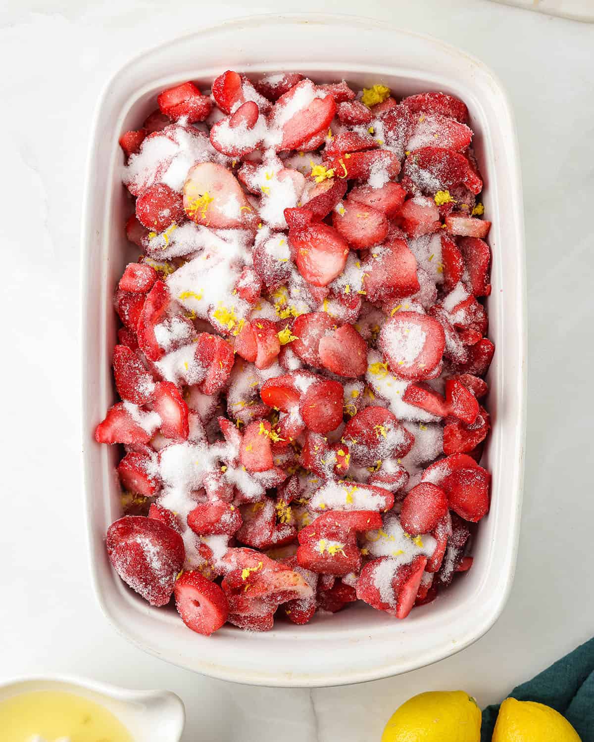 A 9x13 baking dish with strawberries and sugar in it, top view. 